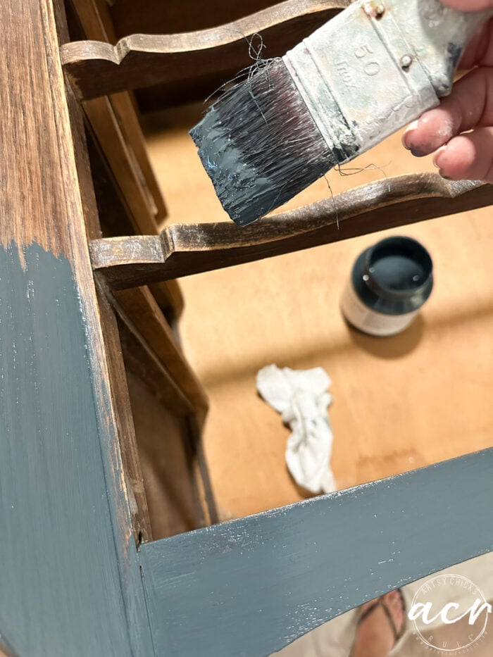 paintbrush applying the blue paint to dresser