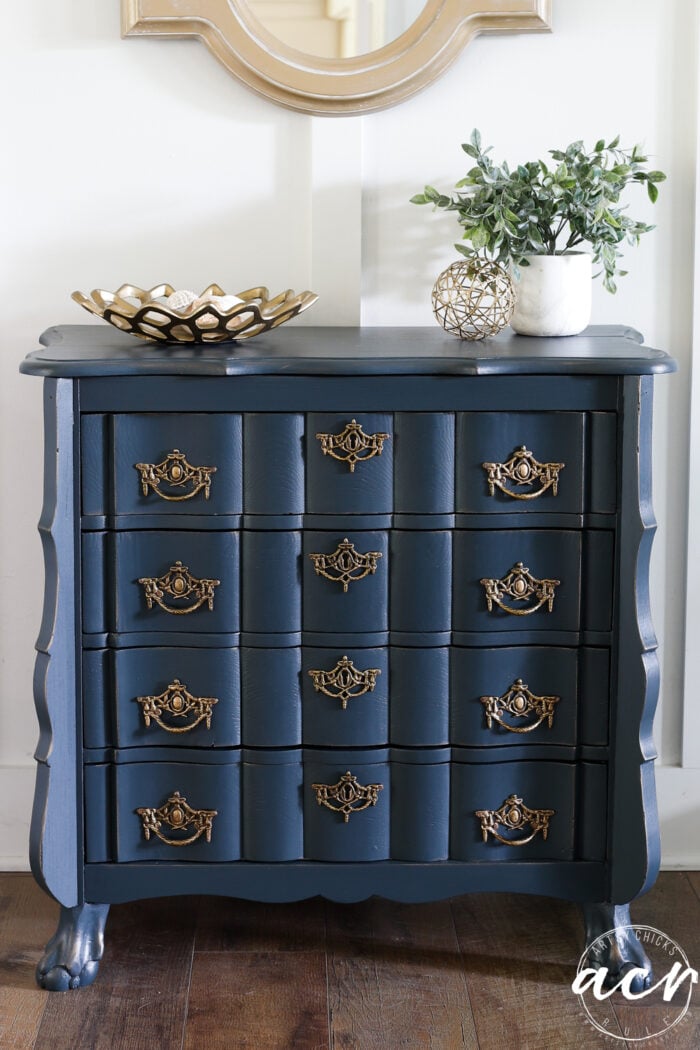 up close of blue dresser decorated on top with plant and gold dish