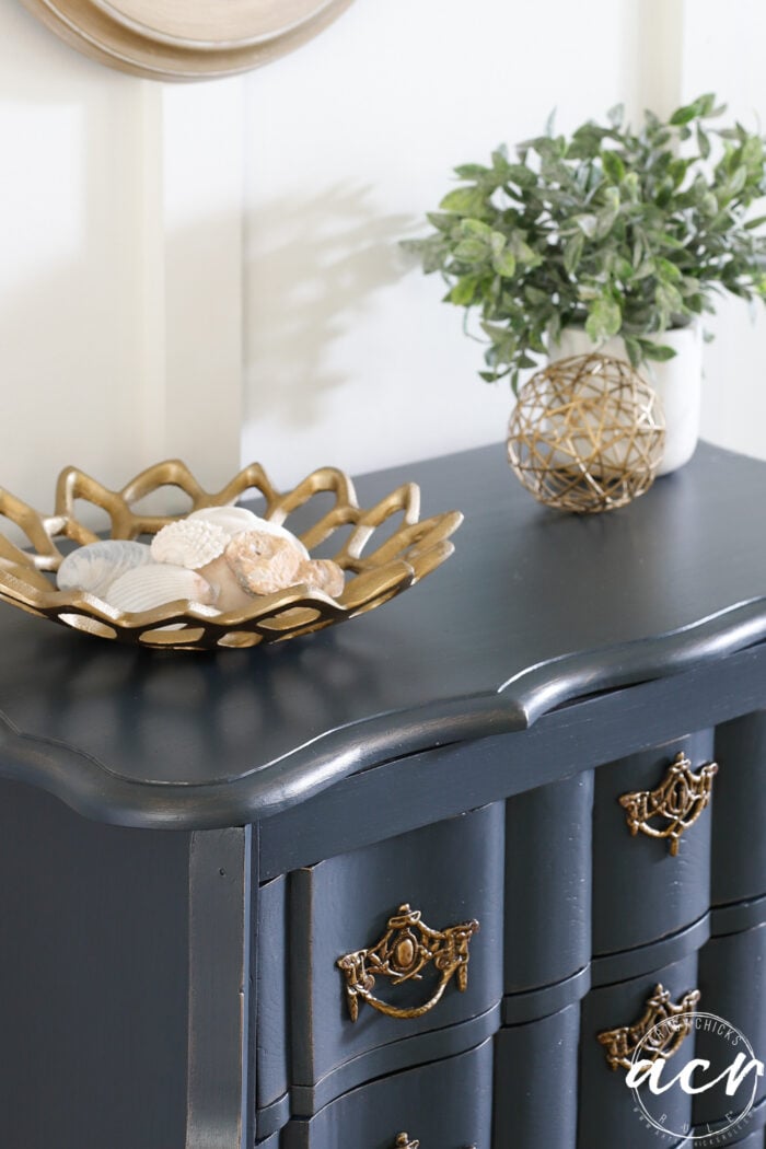up close of blue dresser top with gold dish and green plant